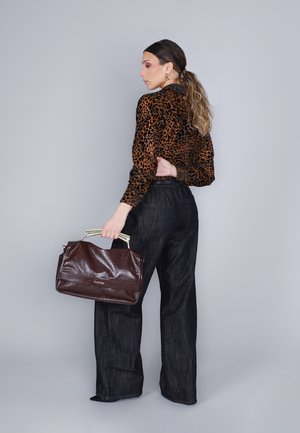 Brun læder håndtaske med guld hardware, blank tekstur. Båret med en leopardmønstret bluse og brede mørkeblå jeans.