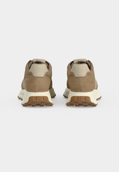 Paire de baskets en daim marron avec semelles crème vues de dos sur un fond clair uni.