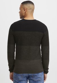 Knitted sweater featuring horizontal black and dark green stripes, long sleeves, and a crew neckline. Fabric texture appears soft and warm.