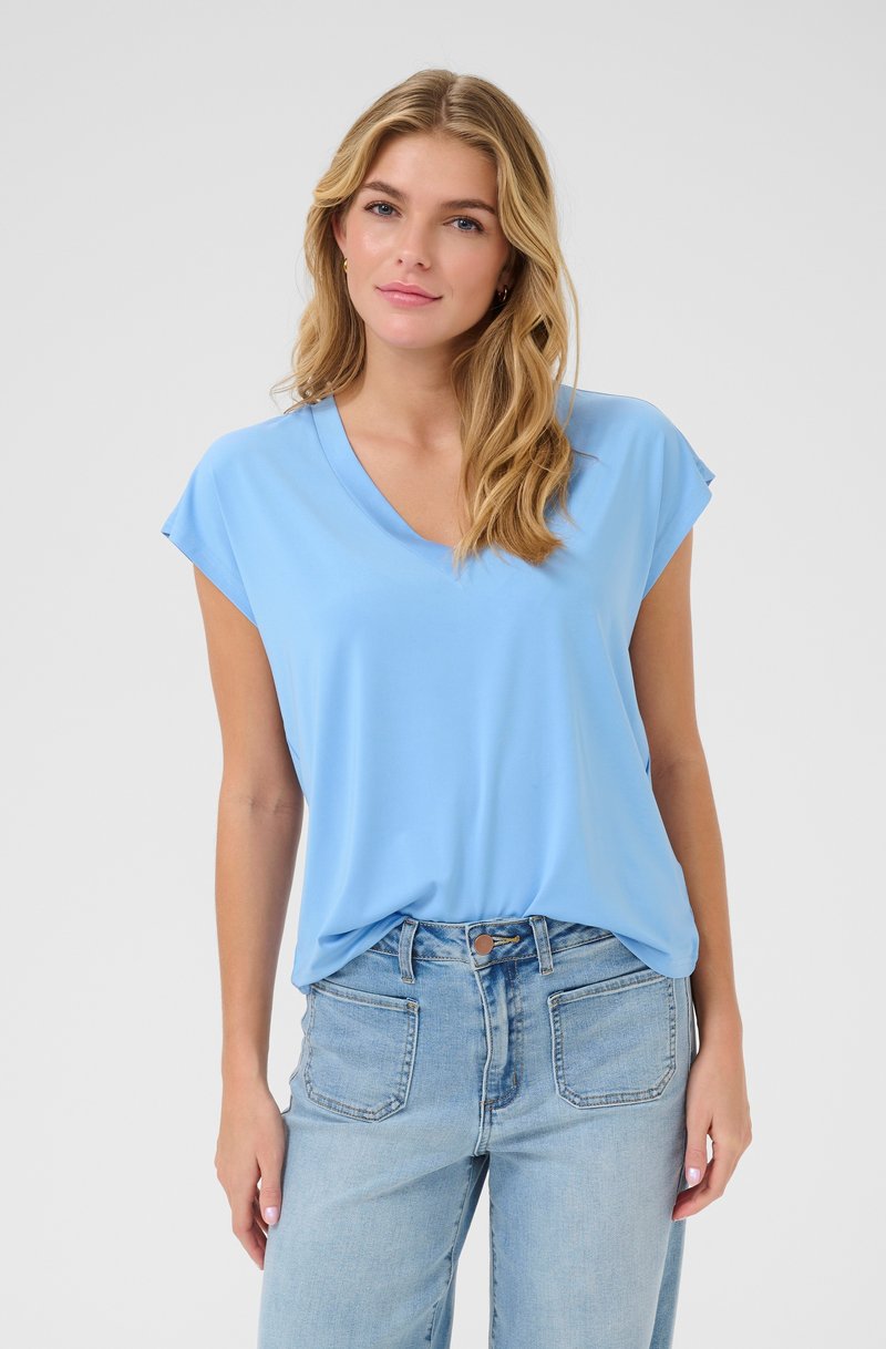 Lichtblauw kortmouwen top met een V-hals ontwerp, gemaakt van zachte stof. Gecombineerd met vervaagde blauwe high-waisted jeans met achterzakken.
