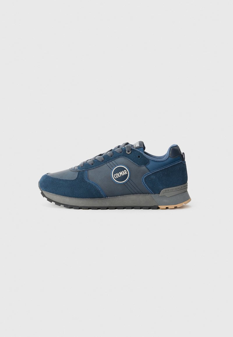Marineblauwe atletische sneaker met een mix van suede en textiele materialen, ronde logopatch, geprofileerde zool en vetersluiting.