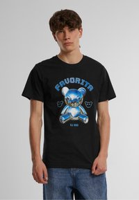 Melnā T-kreklā ir spīdīga zilas krāsas lācīša grafika ar tekstu "FAVORITA" stilizētā zilā fontā virs un maziem lācīša ikonām blakus.