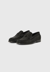 Mocassins noirs en tissu texturé avec des accents scintillants, dotés d'un petit talon et d'un design classique à enfiler. Doublure intérieure lisse.