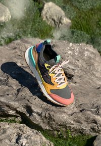 Multi-colored sneaker featuring a mesh upper, leather overlays, and a textured sole. Notable design details include vibrant laces and accents.