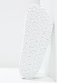 Suela de zapatilla blanca con una superficie texturizada que presenta patrones circulares y una ligera curva. Marcada con la marca "Birki" a lo largo del borde.