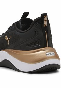 Sneaker nera con accenti dorati, tomaia in sintetico testurizzato, colletto imbottito e suola intermedia bianca e dorata, con il marchio "SOFTRIDE".