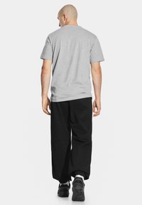 Szary krótki T-shirt z krótkim rękawem i czarne luźne spodnie, w zestawie z czarnymi sneakersami. Prosty design bez widocznych wzorów czy grafik.