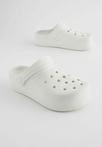 Sabots plateformes blancs en matériau doux, dotés de trous de ventilation, d'un bout arrondi et d'une large sangle lisse sur le coup de pied.