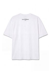 T-shirt blanc à manches courtes vu de dos, avec un petit texte noir près de l'encolure indiquant « ESCAPE THE ORDINARY .»
