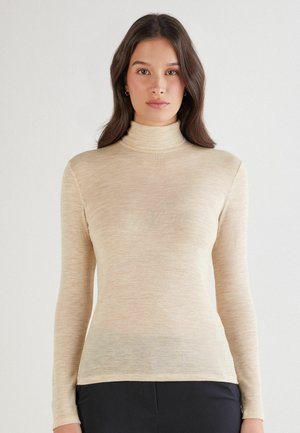 Beige Rollkragenoberteil mit langen Ärmeln. Weicher, strukturierter Stoff zeigt ein dezentes Slub-Muster. Enganliegendes Design mit einem glatten Halsausschnitt.