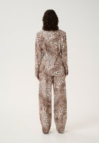 Leopardmønstret jakkesæt med en tætsiddende blazer og vidde bukser. Fremstillet af glat stof med en blanding af beige, brune og sorte nuancer.