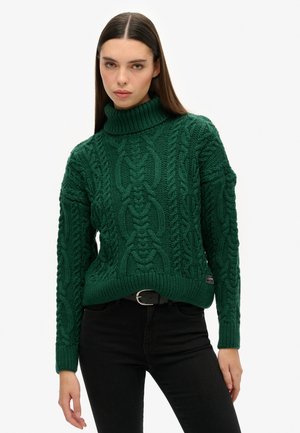 Groene gebreide coltrui met een textuur kabeldesign, geribbelde zoom en manchetten, en een klein merklabel aan de zijkant.