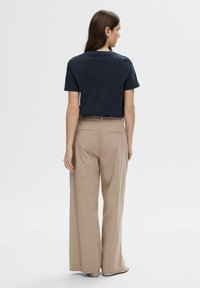 Maritieme katoenen t-shirt, korte mouwen, gecombineerd met beige wijde broek, met een gladde textuur en praktische stiksels op de achterzak.