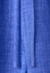 Close-up of blue textured fabric with two vertical stitched strips running parallel in the center.