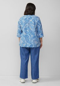 Blauwe blouse met paisleypatroon en driekwartmouwen, gecombineerd met blauwe denimbroek. Beide kledingstukken hebben een ontspannen pasvorm en een casual ontwerp.