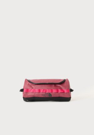 Trousse de toilette rectangulaire rouge et noire avec fermeture à rabat et logo "The North Face" sur le devant, sur un fond clair uni.