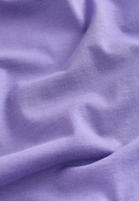 Tissu lavande doux et froissé avec une texture fine en maille, présentant des plis subtils et des ombres à la surface.