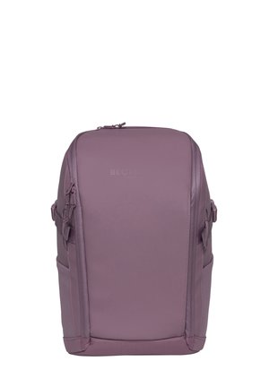 Rektangulær lavendelfarget ryggsekk med to glidelåser på sidene, sidelommer og toppglidelås, stående oppreist mot en ensfarget hvit bakgrunn.