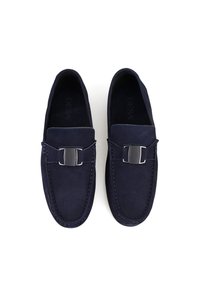 Navy-suede Slipper mit flachem Absatz, metallischem Schnallenakzent und kontrastierenden Nähdetails. Weiche Textur mit einem abgerundeten Design der Zehen.