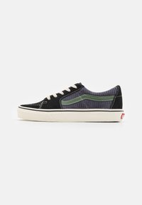 Black and gray sneaker with a textured upper, green accents, white laces, and rubber sole. Features stitching details and classic silhouette.