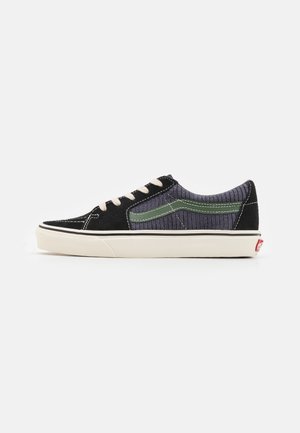 Black and gray sneaker with a textured upper, green accents, white laces, and rubber sole. Features stitching details and classic silhouette.