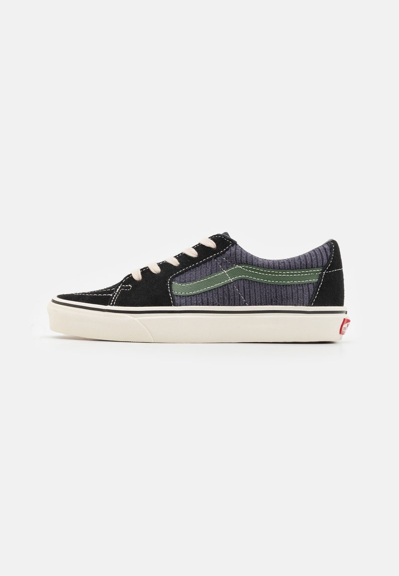 Black and gray sneaker with a textured upper, green accents, white laces, and rubber sole. Features stitching details and classic silhouette.