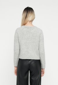 Pull en tricot gris avec un col rond ; présente une bordure texturée et ornée au niveau du col et des manches longues ajustées.