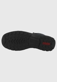 Suola di scarpa nera testurizzata con un motivo a zigzag e un logo rosso, dotata di sezioni ammortizzate per un maggiore comfort e trazione.