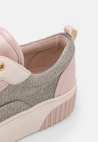 Sneaker rosa con una toma in maglia metallica strutturata, accenti color crema e una suola bianca spessa con scanalature verticali.