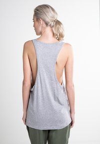 Camiseta sin mangas gris con una espalda baja, hecha de una tela suave y ligera. Presenta grandes sisas y un dobladillo redondeado para mayor comodidad.