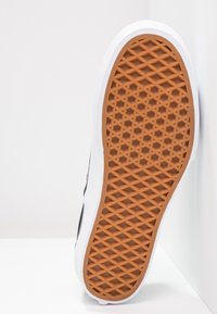 Suela de zapato blanca con un patrón de goma naranja texturizado, que presenta un diseño de cuadrícula hexagonal para ofrecer tracción y durabilidad.