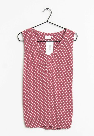 Blusa sin mangas rosa con lunares blancos colgada en una percha negra sobre un fondo blanco, mostrando el frente y el escote.