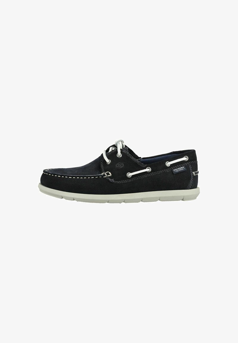 Schwarzer Mokassinschuh aus Wildleder mit weißen Schnürsenkeln und Nähten, weißer Gummisohle und seitlichem Logoetikett vor weißem Hintergrund.