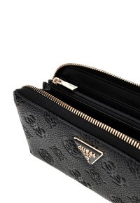 Portefeuille noir texturé avec fermeture éclair et accents dorés, comprenant un compartiment zippé et un motif de surface.