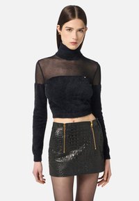 Schwarzer, kurz geschnittener Pullover mit einem enganliegenden Rollkragen, aus strukturiertem Material; kombiniert mit einem schwarzen, ledernen Minirock mit Reißverschlussakzenten.