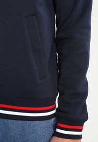 Marine sweatshirt met ribbelmanchetten, voorzien van rode, witte en zwarte strepen. Inclusief een zijzak en textuurstof.