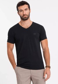 Czarny bawełniany t-shirt z dekoltem w szpic i krótkimi rękawami. Posiada małe logo "EX" na lewej piersi. Gładka tekstura.