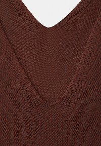 Gros plan sur un tissu marron tricoté montrant un détail d'encolure en V avec un motif de fil texturé et des points de tricot visibles.