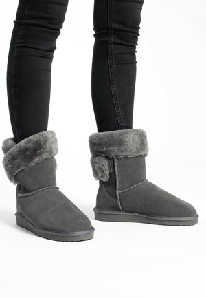 Bottes ankle en suede gris avec un doux revers en fausse fourrure grise, semelle en caoutchouc plate et détails cousus le long des coutures.
