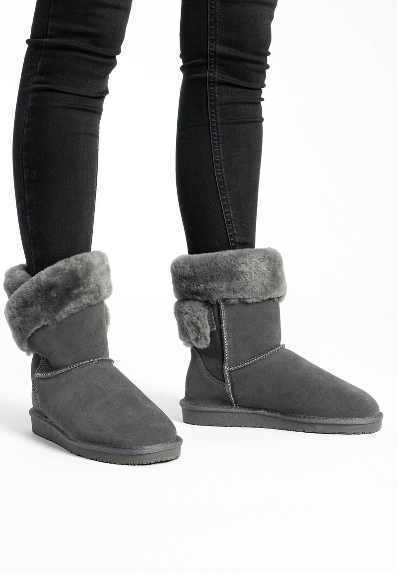Botines de ante gris con un suave puño de piel sintética gris, suela plana de goma y detalles cosidos a lo largo de las costuras.