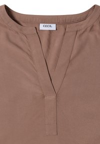Camicia marrone con scollo a V, caratterizzata da una trama liscia e cuciture pulite. L'etichetta mostra "CECIL" all'altezza dello scollo.