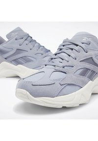 Ljuslila träningsskor i mocka och nätmaterial, med en strukturerad yta, vit gummisula och framträdande snörningsdesign.