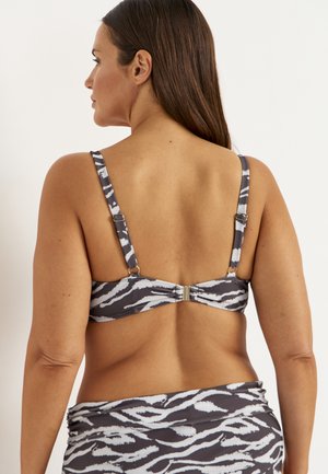 Kvinde set bagfra iført en grå og hvid bikini med zebrastriber med matchende underdel med justerbare stropper og lukning med spænde.