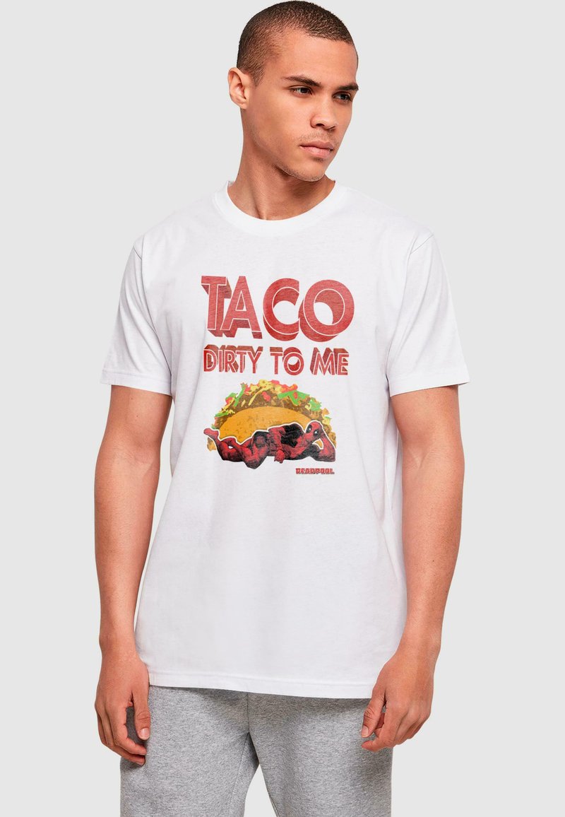 Balta medvilninė marškinė su išryškintu raudonu tekstu "TACO DIRTY TO ME" ir taco grafika bei personažu raudonais drabužiais.