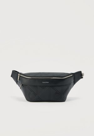 Riñonera de cuero negro Calvin Klein con patrón en relieve de CK y cremallera plateada sobre fondo liso.