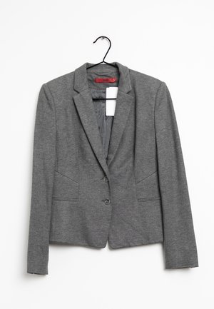 Szara dopasowana marynarka z dwoma frontowymi guzikami i bocznymi kieszeniami, zawieszona na czarnym wieszaku na białym tle.