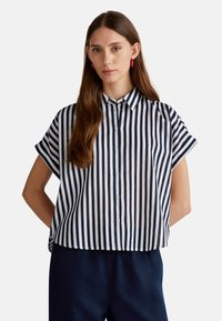 Camicetta a righe navy e bianche con maniche corte, design con bottoni, caratterizzata da un colletto e un fit rilassato. Tessuto morbido e leggero.