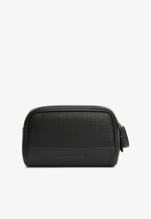 Bolsa de aseo rectangular negra con la mitad superior texturizada, la mitad inferior lisa, cierre de cremallera en la parte superior y pequeño logo de Tommy Hilfiger en el frente.
