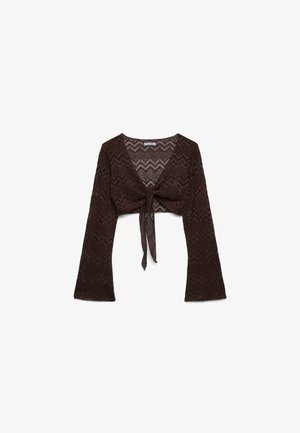 Top corto marrone all'uncinetto a maniche lunghe con motivo a chevron e nodo frontale, caratterizzato da una scollatura a V profonda e maniche leggermente svasate.