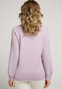 Pull violet clair en tissu doux et texturé, avec des manches longues et des accents de boutons au poignet, présentant une coupe décontractée et un ourlet côtelé.